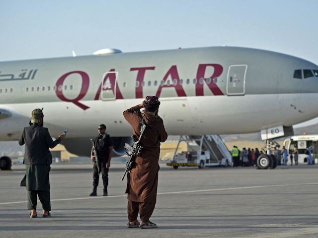 A Qatari security personnel (2L) and Taliban fighters stand guard as passengers board a Qatar Airways aircraft at the airport in Kabul on September 9, 2021. - Some 200 passengers, including US citizens, left Kabul airport on September 9, 2021, on the first flight carrying foreigners out of the Afghan capital since a US-led evacuation ended on August 30. (Photo by WAKIL KOHSAR / AFP) (Photo by WAKIL KOHSAR/AFP via Getty Images)