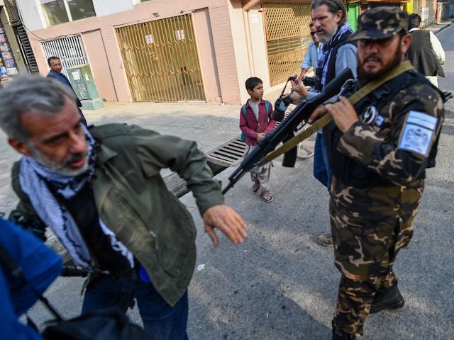 A member of the Taliban special forces pushes a journalist (L) covering a demonstration by women protestors outside a school in Kabul on September 30, 2021. (Bulent Kilic/AFP via Getty Images)