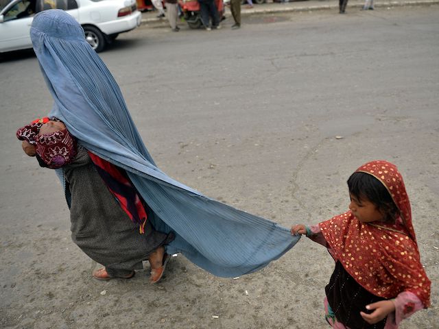 A burqa-clad woman walks with her children along a street in Kabul on August 31, 2021. (Photo by Hoshang Hashimi/AFP via Getty Images)