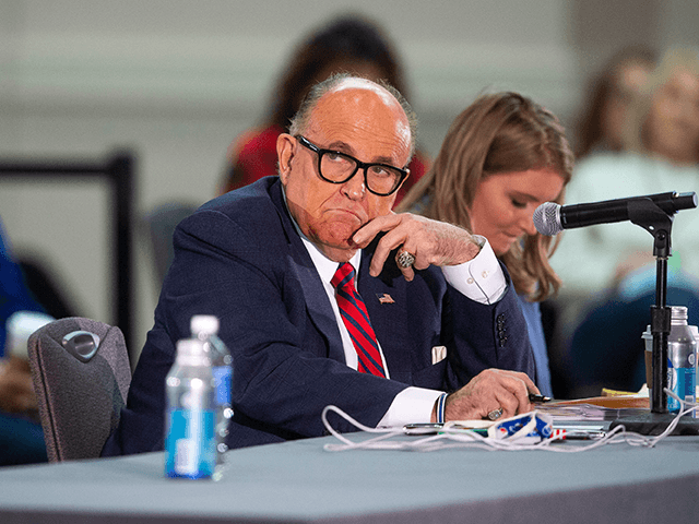 President Donald Trump's attorney Rudy Giuliani listens to presenters at a public meeting