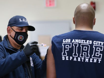 LOS ANGELES, CALIFORNIA - JANUARY 29: A Los Angeles Fire Department (LAFD) firefighter receives a Moderna COVID-19 vaccination dose from firefighter Michael Perez (L) at a fire station on January 29, 2021 in Los Angeles, California. LAFD has recorded a ‘sharp decline’ in coronavirus cases after firefighters began receiving the …