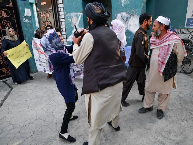 A woman protestor scuffles with a member of the Taliban during a demonstration outside a school in Kabul on September 30, 2021. (Bulent Kilic/AFP via Getty Images)