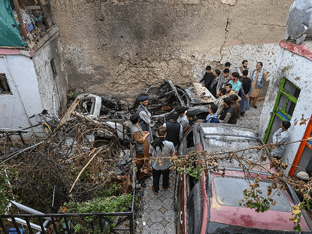 Afghan residents and family members of the victims gather next to a damaged vehicle inside a house, after a US drone strike which they say went wrong in Kabul