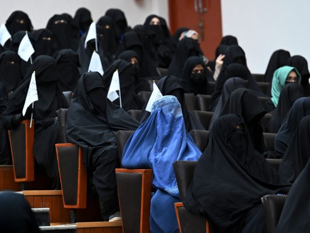 Veiled students hold Taliban flags as they listen a speaker before a pro-Taliban rally at