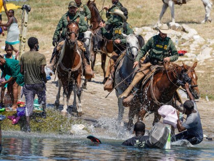 United States Border Patrol agents on horseback tries to stop Haitian migrants from enteri
