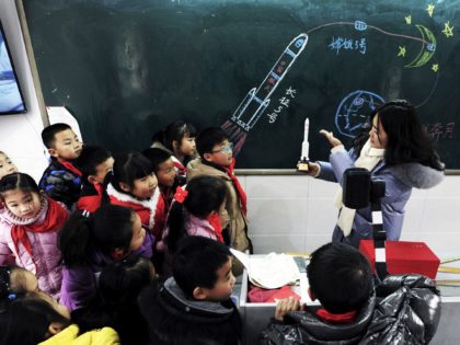A teacher shows a model of the Longmarch rocket to children during an aerospace education