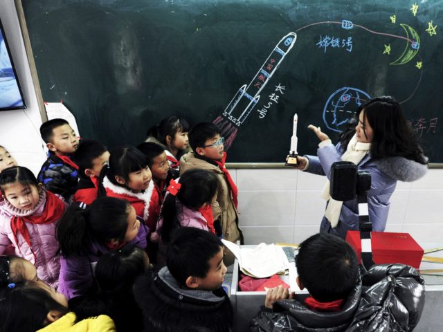A teacher shows a model of the Longmarch rocket to children during an aerospace education lesson at a primary school in Yunyang county in southwestern China's Chongqing on December 16, 2020. (Photo by STR / AFP) / China OUT (Photo by STR/AFP via Getty Images)