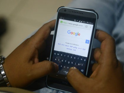 An Indian man surfs on his mobile phone using the Google search engine with its new logo,