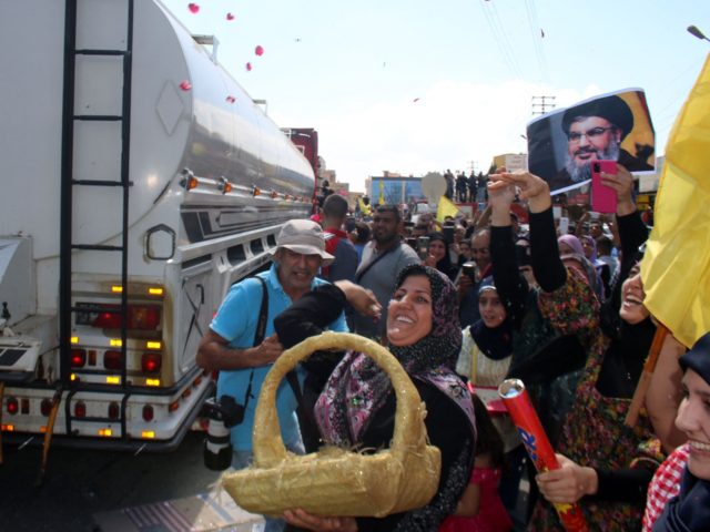 A woman tosses rose petals as people gather to welcome tankers carrying Iranian fuel, upon their arrival from Syria in the city of Baalbeck, in Lebanon's Bekaa valley, on September 16, 2021. - Dozens of tankers carrying Iranian fuel and transported by the Shiite Hezbollah movement arrived from Syria in …