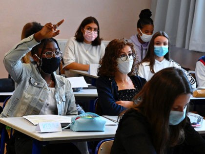 A girl with a protective mask raises his hand as pupils sit in a classroom in Brequigny high school in Rennes, western France, on September 1, 2020 on the first day of the school year amid the Covid-19 epidemic. - French pupils go back to school on September 1 as …