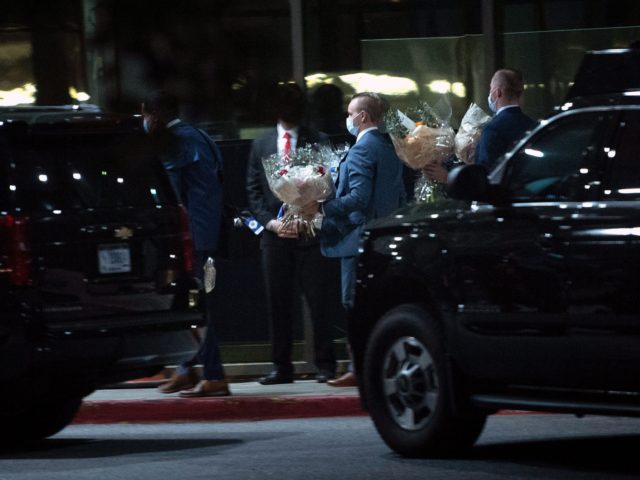 Staff carry flowers from a motorcade as US President Joe Biden and US first lady Jill Bide