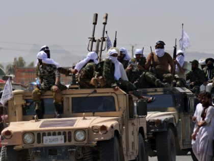 Taliban fighters atop Humvee vehicles parade along a road to celebrate after the US pulled