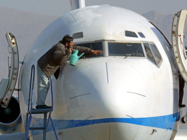 An airport worker washes the windshield of an Ariana Afghan Airlines plane before it makes