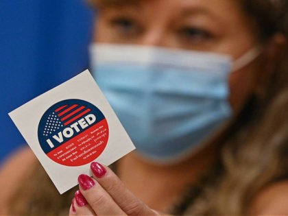 A poll worker holds up an "I Voted" sticker in the California gubernatorial recall election at a polling station at Burbank High School in Burbank, California, September 14, 2021. - Voters went to the polls in California on Tuesday to decide whether to oust the Democratic governor of the most-populous …