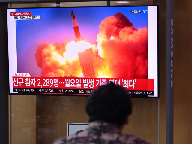 People watch a television news broadcast showing file footage of a North Korean missile te