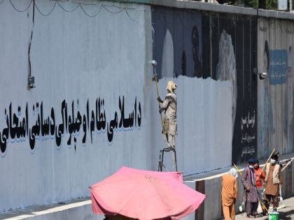 TOPSHOT - A man paints over murals on a concrete wall with a message reading "For an Islamic system and independence, you have to go through tests and stay patient", in Kabul on September 4, 2021. (Photo by Aamir QURESHI / AFP) (Photo by AAMIR QURESHI/AFP via Getty Images)