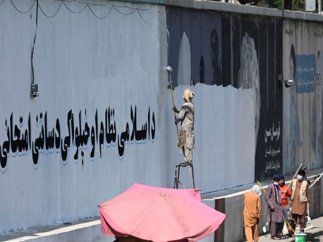 TOPSHOT - A man paints over murals on a concrete wall with a message reading "For an Islam