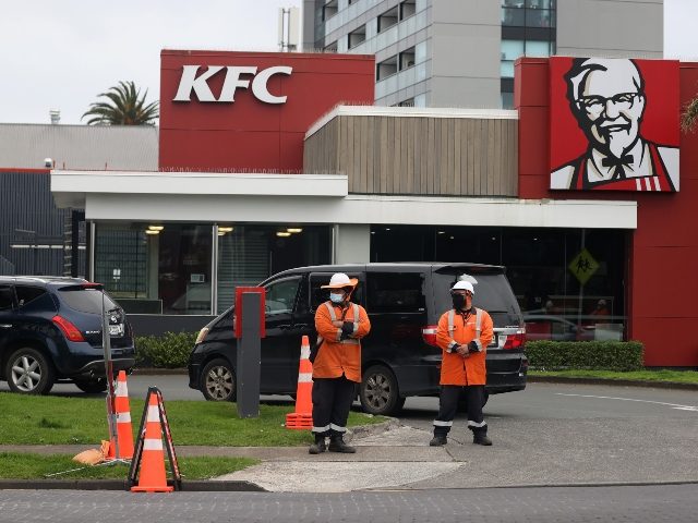 AUCKLAND, NEW ZEALAND - SEPTEMBER 22: Traffic management workers direct a large queue of cars through the KFC drive through in Manukau on September 22, 2021 in Auckland, New Zealand. Restrictions have eased for Auckland residents, with the Greater Auckland area moving to COVID-19 Alert Level 3 settings from 11:59pm …