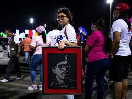 A youth carries a portrait of Nicaraguan President Daniel Ortega during commemorations for the anniversary of the triumph of the 1979 Sandinista Revolution that toppled dictator Anastasio Somoza in Managua, Nicaragua, late Sunday, July 18, 2021. (AP Photo/Miguel Andrés)