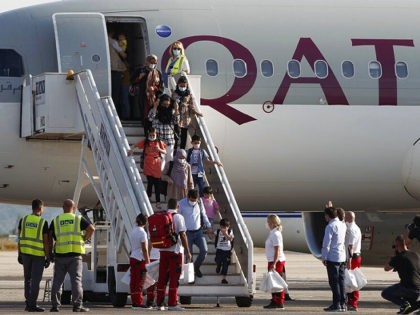 Afghan evacuees disembark the plane to board a bus after landing at Skopje International A