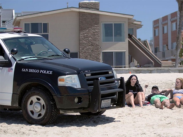 FILE - In this May 22, 2020, file photo, San Diego police officers ask three people to get up from the beach, which was closed to sitting or lying down, in San Diego. California is creating roving "strike teams" drawn from seven state agencies that will enforce state guidelines designed …