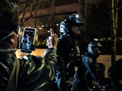 SEATTLE, WA - APRIL 12: (EDITORS NOTE: Image depicts obscene gesture) A person records police officers at a protest over the death of Daunte Wright on April 12, 2021 in Seattle, Washington. Wright, a Black man whose car was stopped in Brooklyn Center, Minnesota on Sunday reportedly for an expired …