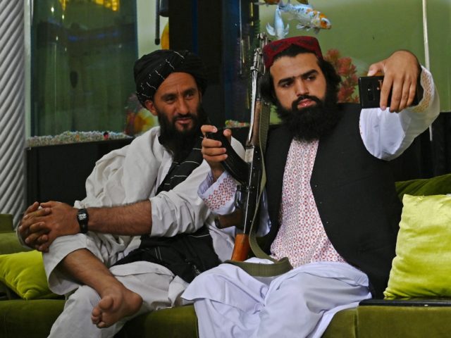 In this picture taken on September 11, 2021, Taliban fighters take their selfie with a mob