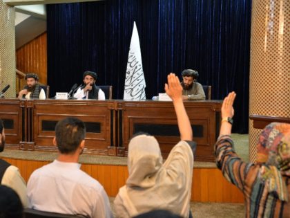 Taliban spokesperson Zabihullah Mujahid (C) gestures towards journalists raising their han