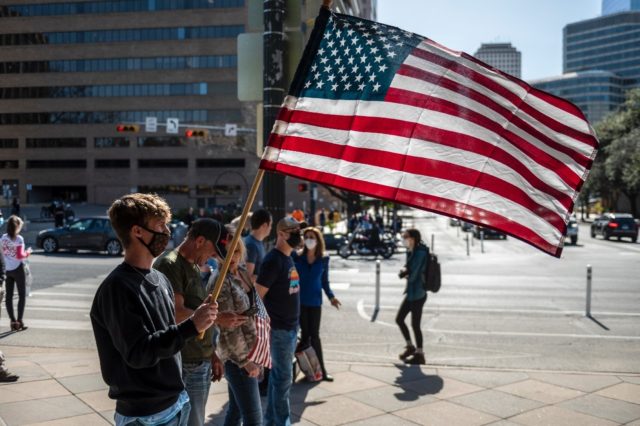 A young man holds an American flag in January 2021 outside the State Capitol in Texas, whi
