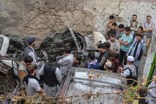 Afghan relatives gather on August 30, 2021 next to a damaged vehicle after a US drone stri