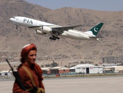 A Taliban fighter stands guard as a Pakistan International Airlines plane takes off from K