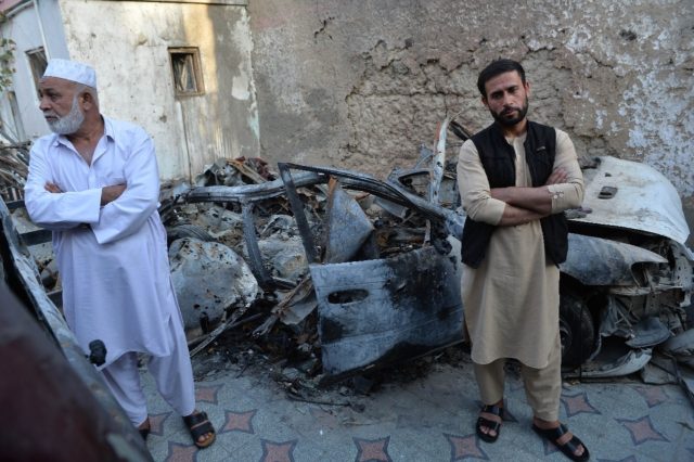 Aimal Ahmadi (R), brother of Ezmarai Ahmadi, who was one of 10 people killed in a US drone strike in Kabul that the US now says was a mistake, stands next to the wreckage of a vehicle destroyed in the attack