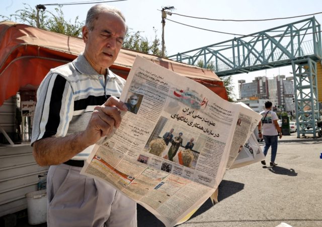 An Iranian man reads a copy of the daily newspaper "Etalaat" headlined, "Iran is a new mem