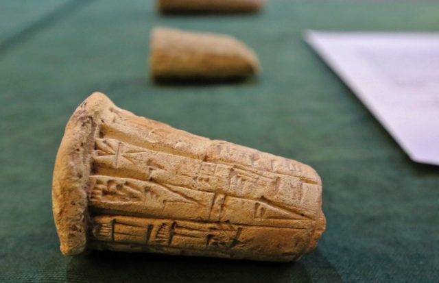 Mesopotamian clay cones bearing cuneiform inscriptions are displayed during a handover cer
