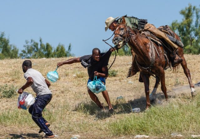 A United States Border Patrol agent on horseback tries to stop a Haitian migrant from ente