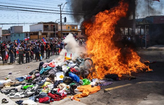 Demonstrators burn belongings at a makeshift Venezuelan migrant camp during a protest in I