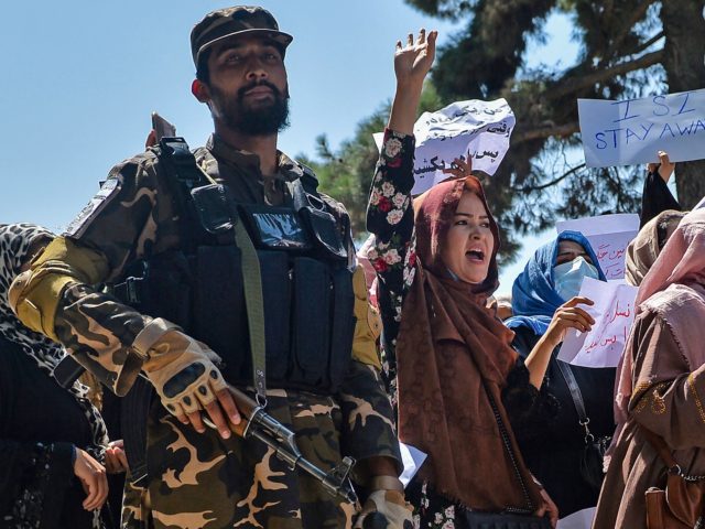 Afghan women shout slogans next to a Taliban fighter during an anti-Pakistan demonstration near the Pakistan embassy in Kabul on September 7, 2021. - The Taliban on September 7, 2021 fired shots into the air to disperse crowds who had gathered for an anti-Pakistan rally in the capital, the latest …