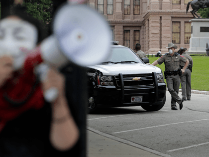 State troopers watch as protesters rally at the Texas State Capitol to speak out against Texas' handling of the COVID-19 outbreak, in Austin, Texas, Saturday, April 18, 2020. Austin and many other Texas cities remain under stay-at-home orders due to the COVID-19 outbreak except for essential personal. (AP Photo/Eric Gay)