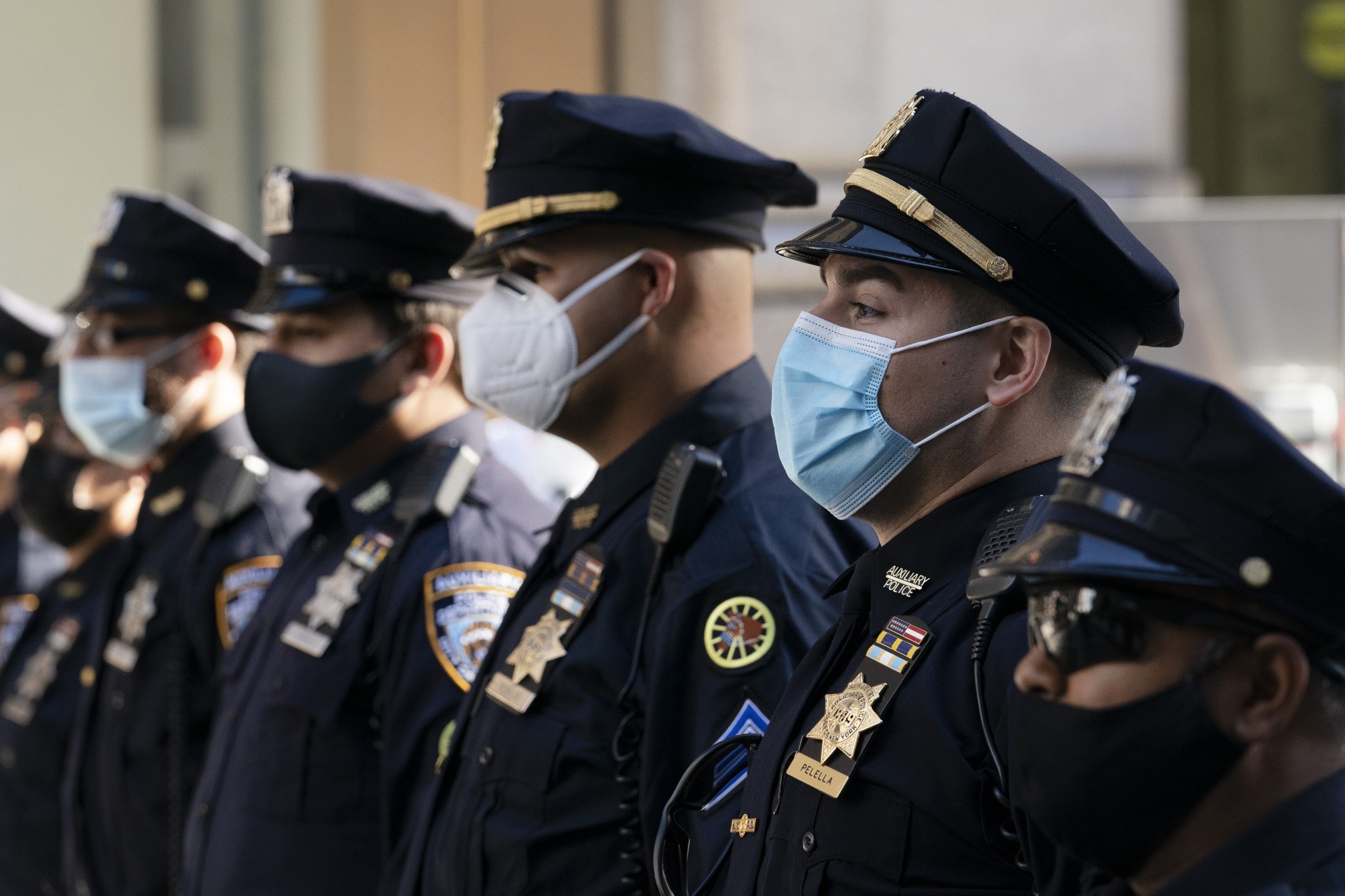 FILE - In this Oct. 5, 2020, file photo, New York Police Department officers in masks stand during a service at St. Patrick's Cathedral in New York to honor 46 colleagues who have died due to COVID-19 related illness. New York City will require police officers, firefighters and other municipal workers to be vaccinated against COVID-19 or be placed on unpaid leave, Mayor Bill de Blasio said Wednesday, Oct. 20, 2021, giving an ultimatum to public employees who’ve refused and ensuring a fight with some of the unions representing them. (AP Photo/Mark Lennihan, File)