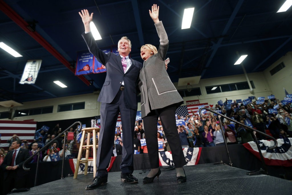 FILE This Monday Feb. 29, 2016 file photo shows Virginia Gov. Terry McAuliffe, left, waves to the crowd along with Democratic presidential candidate Hillary Clinton as she arrives to speak at a campaign rally in Norfolk, Va. Virginia was supposed to be a key battleground state and the high energy governor was expected to spend the weeks leading up to Election Day bouncing around the Old Dominion to help longtime pal Hillary Clinton win the state's 13 electoral votes. (AP Photo/Gerald Herbert)