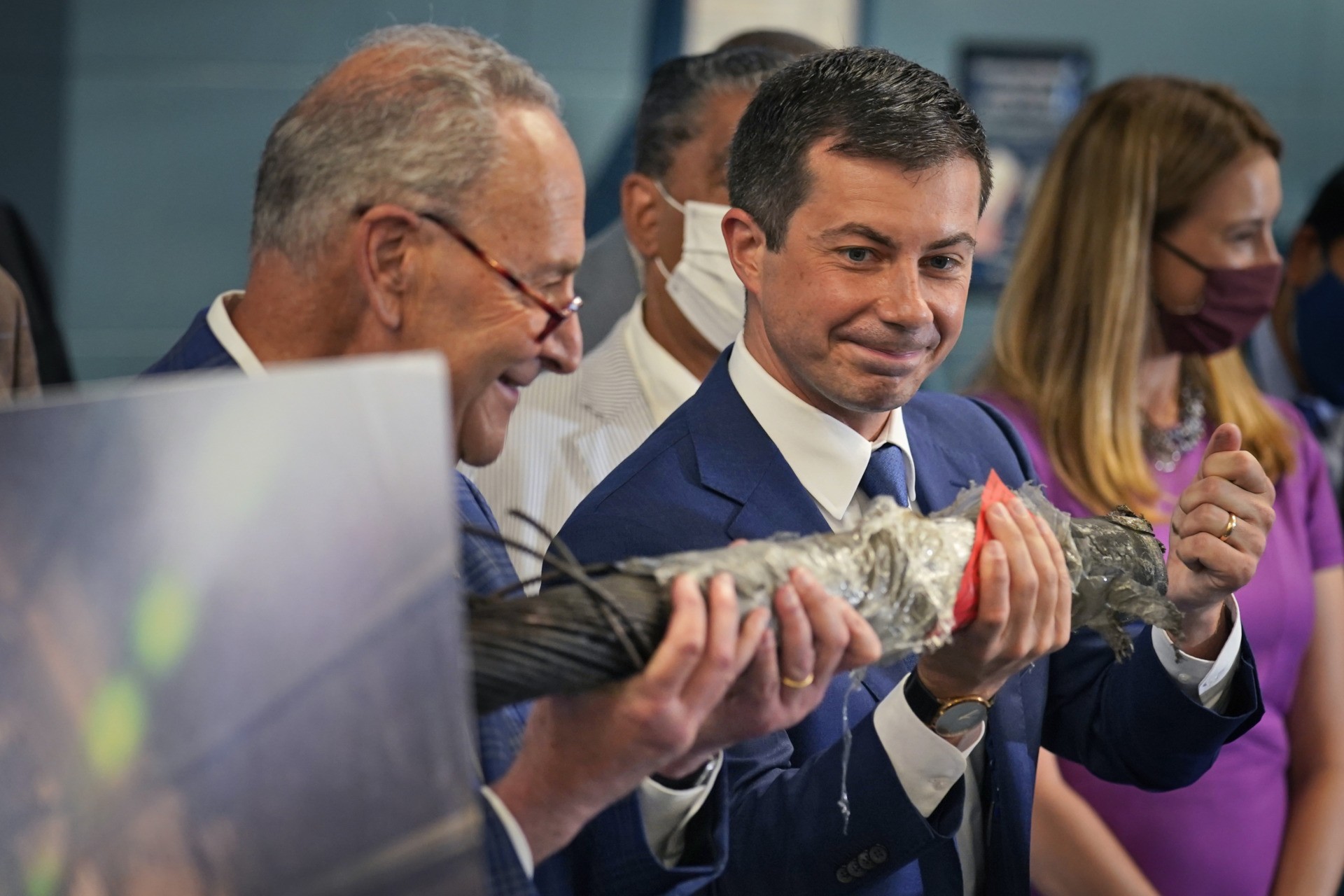 Secretary of Transportation Pete Buttigieg, right, and Sen. Chuck Schumer, D-N.Y., hold a decaying piece of a rail tunnel while they speak during a news conference in New York, Monday, June 28, 2021. Buttigieg toured the century-old rail tunnel connecting New York and New Jersey as a long-delayed project to build a new tunnel gains steam. (AP Photo/Seth Wenig)