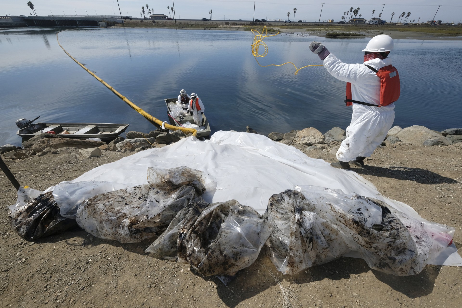 Cleanup contractors collect oil in plastic bags trying to stop further oil crude incursion into the Wetlands Talbert Marsh in Huntington Beach, Calif., Sunday, Oct. 3, 2021. One of the largest oil spills in recent Southern California history fouled popular beaches and killed wildlife while crews scrambled Sunday to contain the crude before it spread further into protected wetlands. (AP Photo/Ringo H.W. Chiu)