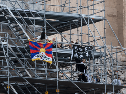 Protesters raise a Tibetan flag and a banner from scaffolding at the Acropolis hill, in Athens, Greece, Sunday, Oct. 17, 2021. Three people attempted to hang a banner from the Acropolis in Athens Sunday morning in protest at the upcoming Beijing Winter Olympics but were arrested before completing their mission. …