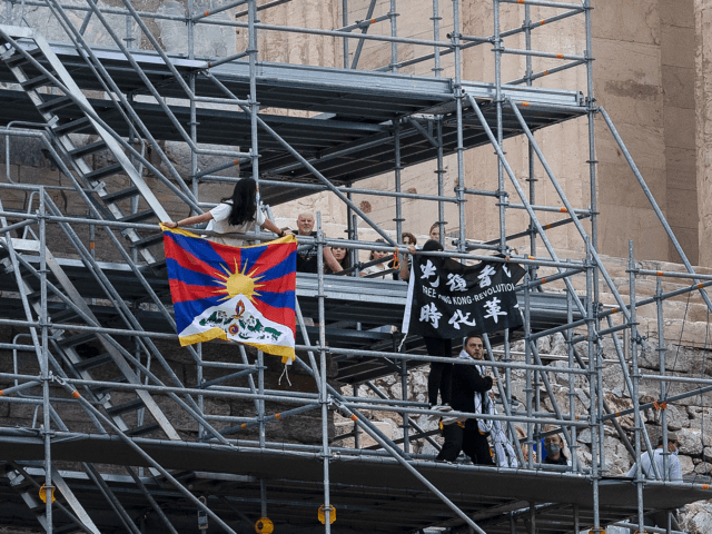 Protesters raise a Tibetan flag and a banner from scaffolding at the Acropolis hill, in At
