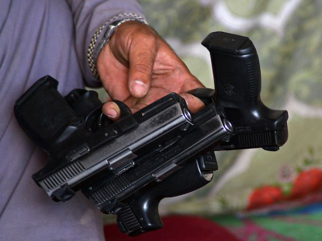 An Afghan vendor holds pistols to display for sale while waiting for customers in his shop at a market in Panjwai district of Kandahar province on September 4, 2021. (Javed Tanveer/AFP via Getty Images)