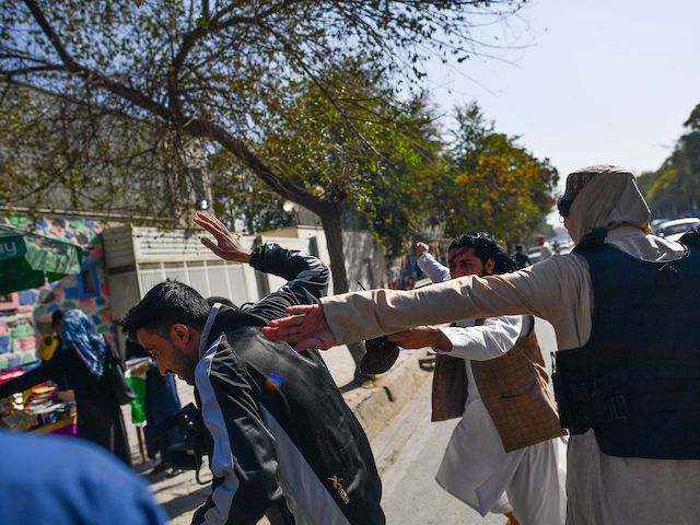 Taliban members (R) attack journalists covering a women's rights protest in Kabul on October 21, 2021. (Bulent Kilic/AFP via Getty Images)