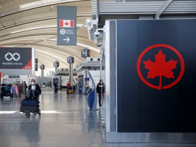 A passenger wheels his luggage near an Air Canada logo at Toronto Pearson International Airport on April 1, 2020 in Toronto, Canada. Air Canada announced it would temporarily lay off over 15,000 employees and reduce activity by up to 90 percent due to the coronavirus. (Photo by Cole Burston/Getty Images)