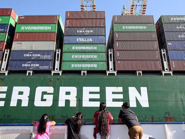 People ride on a tour boat beneath cargo containers stacked on a container ship at the Port of Los Angeles, the nation’s busiest container port, on October 15, 2021 in San Pedro, California. (Mario Tama/Getty Images)
