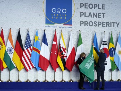 Workers adjust a flag prior to a group photo at the G20 summit in Rome, Saturday, Oct. 30,