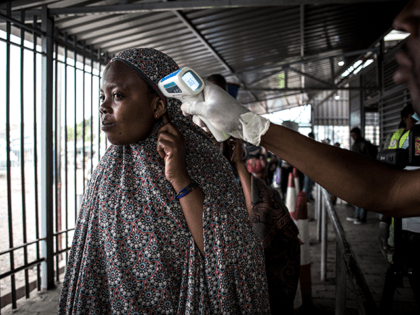 A woman gets her temperature measured at an Ebola screening station as she enters the Democratic Republic of the Congo from Rwanda on July 16, 2019 in Goma. - The first patient to be diagnosed with Ebola in the eastern DR Congo city of Goma has died, the governor of …